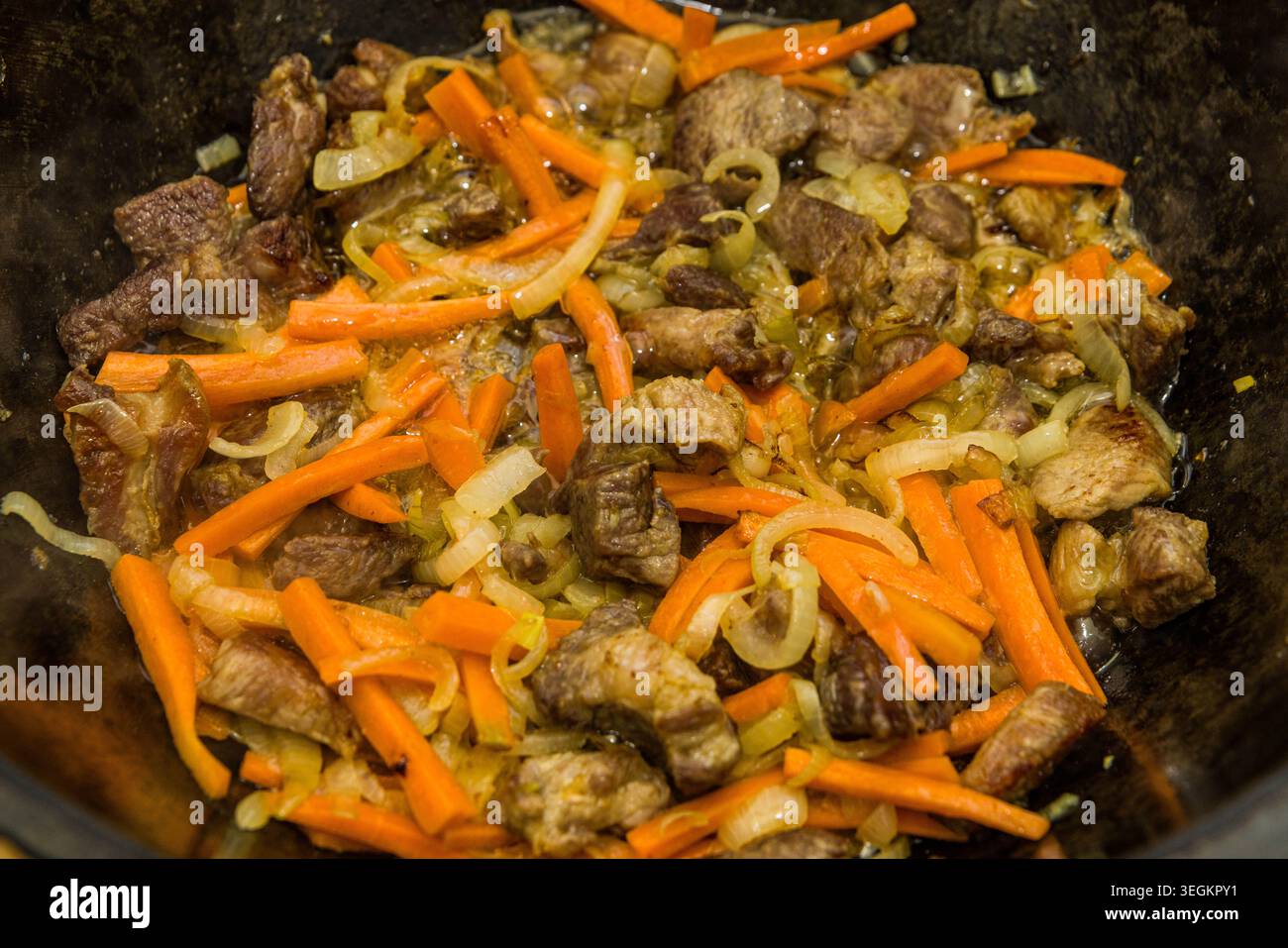 Lammfleisch, Zwiebeln und Karotten in traditionellem kasan für usbekische Plov-Zubereitung, authentisches hausgemachtes asiatisches Kochrezept. Stockfoto