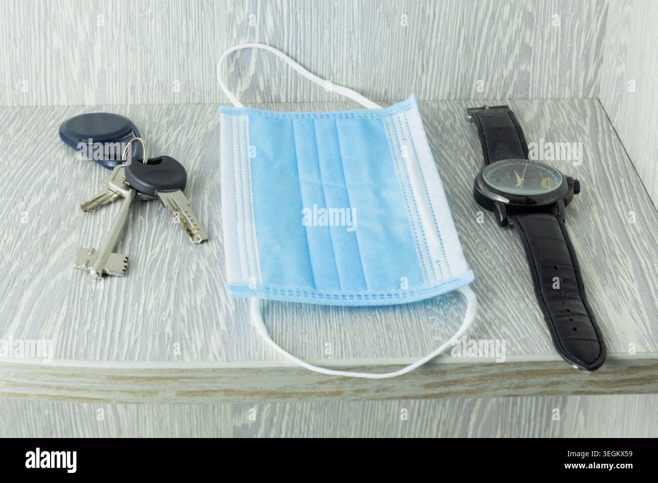 Eine Einwegmaske, Schlüssel, eine Uhr, im Regal Stockfoto