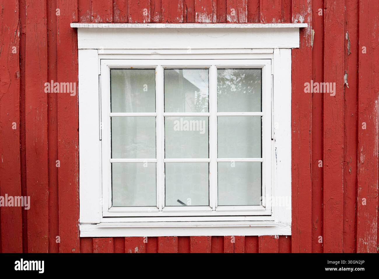 Weiß gerahmtes Fenster auf roter Holzfassade in traditioneller skandinavischer Architektur Stockfoto