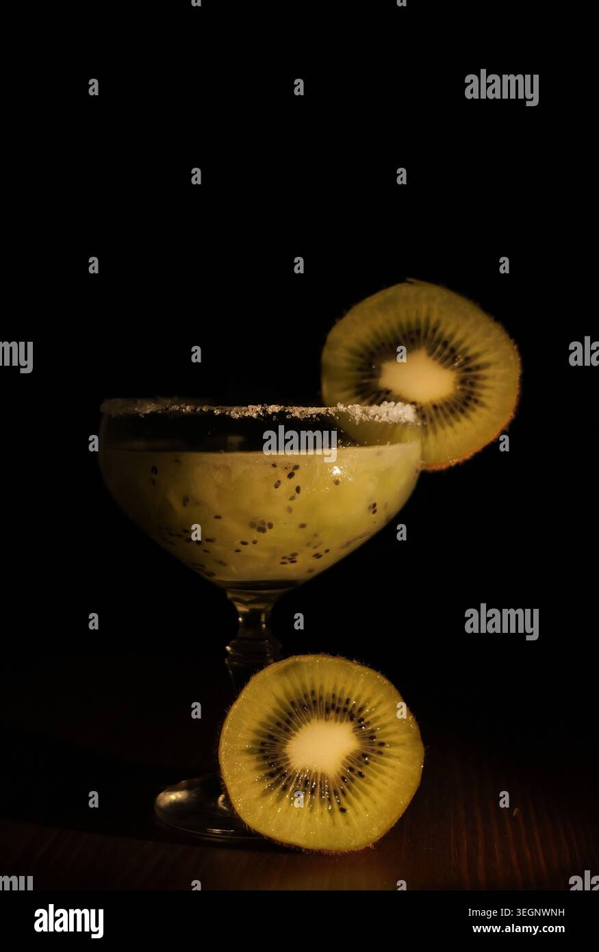 Kiwi-Fruchtcocktail in einem Glas mit Zuckerrand, garniert mit frischen Kiwi-Scheiben, ein erfrischendes Getränk auf dunklem Hintergrund Stockfoto