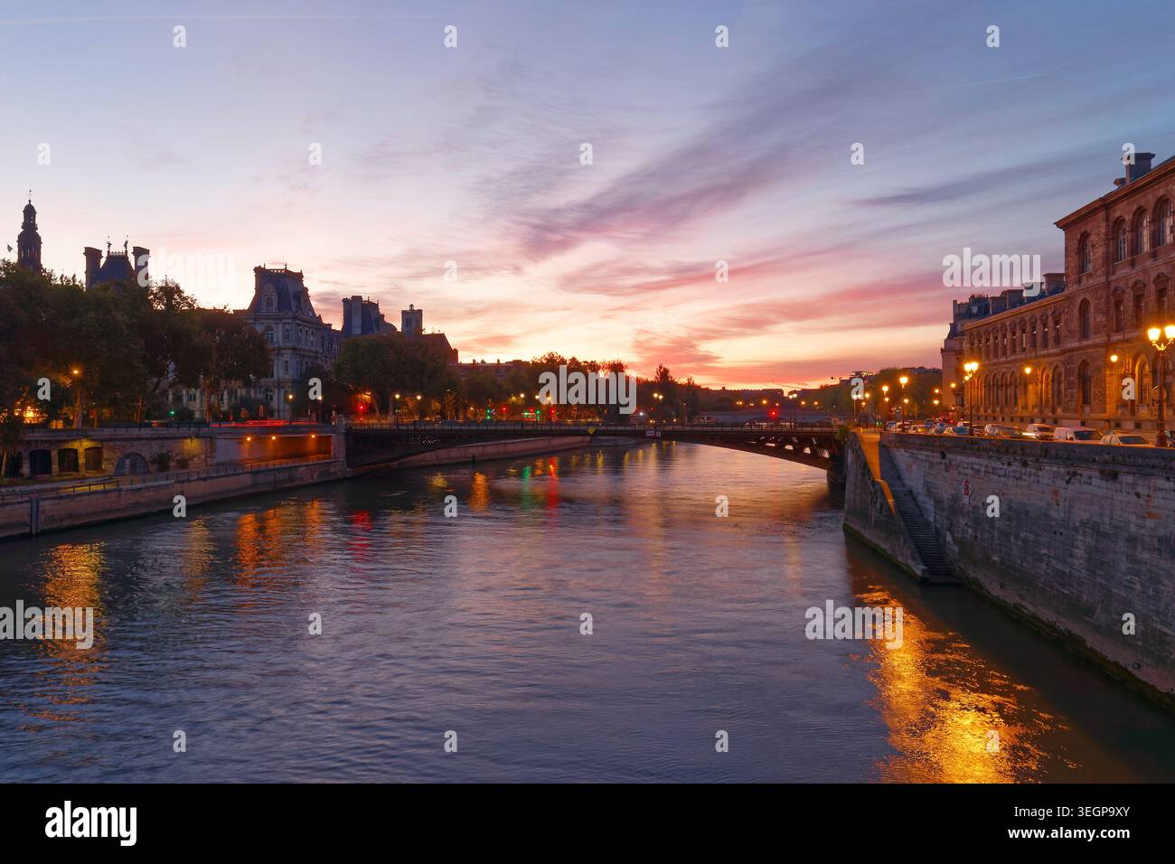 Atemberaubender Sonnenuntergang über der seine in Paris, mit der Silhouette des H tel de Ville im goldenen Wasser. Eine Steinbrücke überspannt den Stockfoto