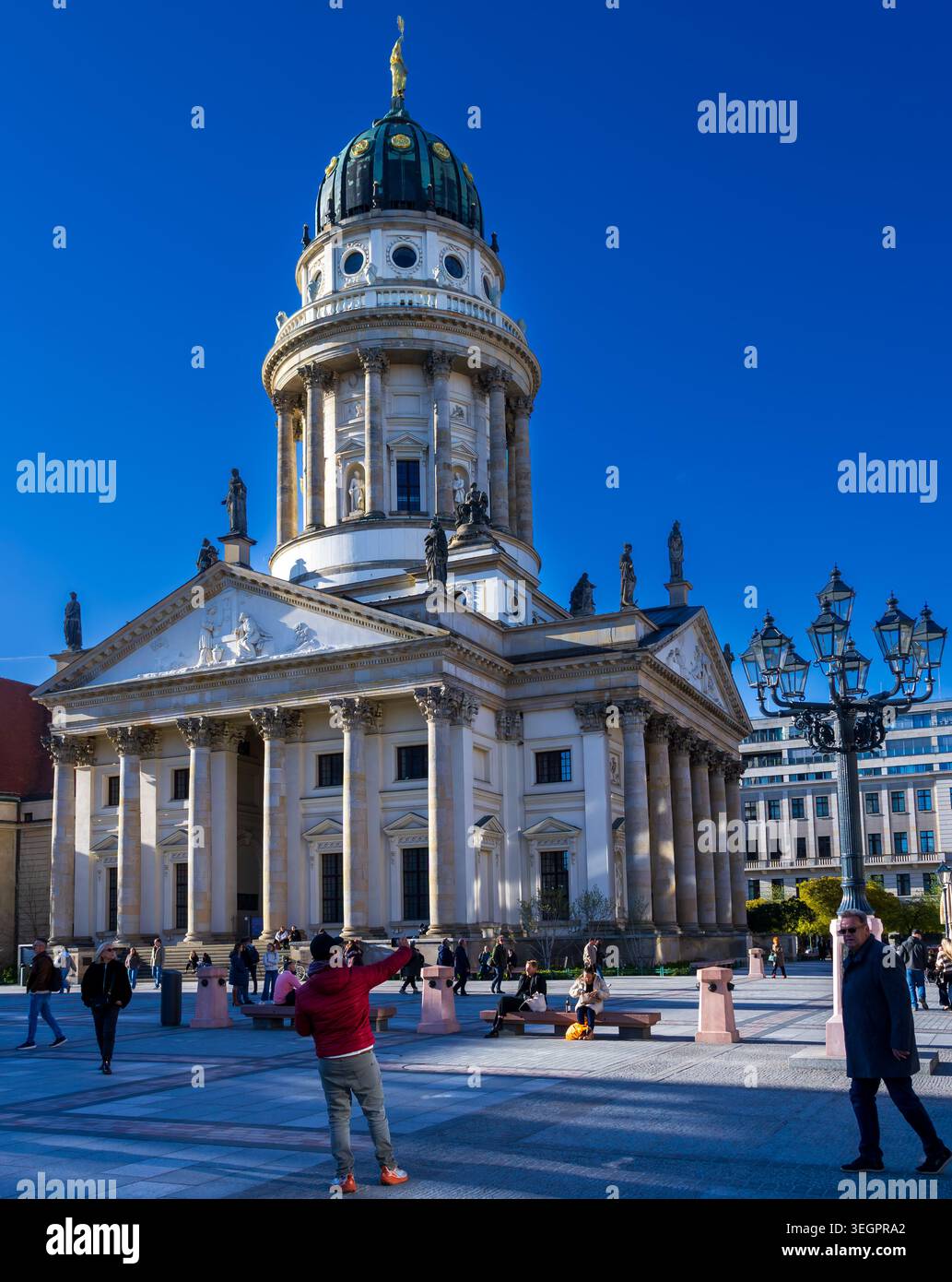 Besucher und Touristen am Gendarmenmarkt vor dem Französischen Dom in Berlin Mitte, Deutschland, an einem sonnigen Frühlingstag. Stockfoto