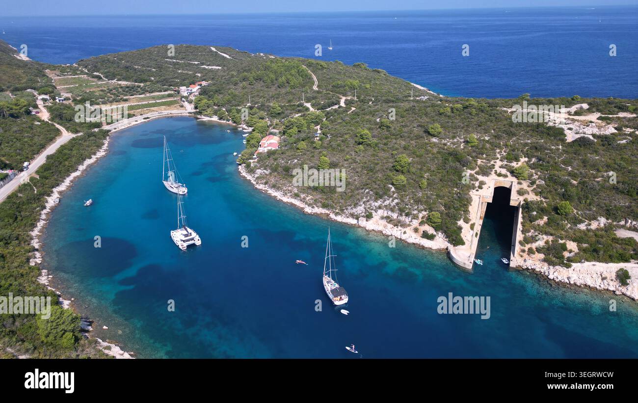 Blick aus der Vogelperspektive auf den Bootsunterstand Potkop Parja und Segelboote in einer türkisfarbenen Bucht, umgeben von üppigen grünen Hügeln in Rogacic, Splitsko-dalmatinska, Kroatien. Stockfoto