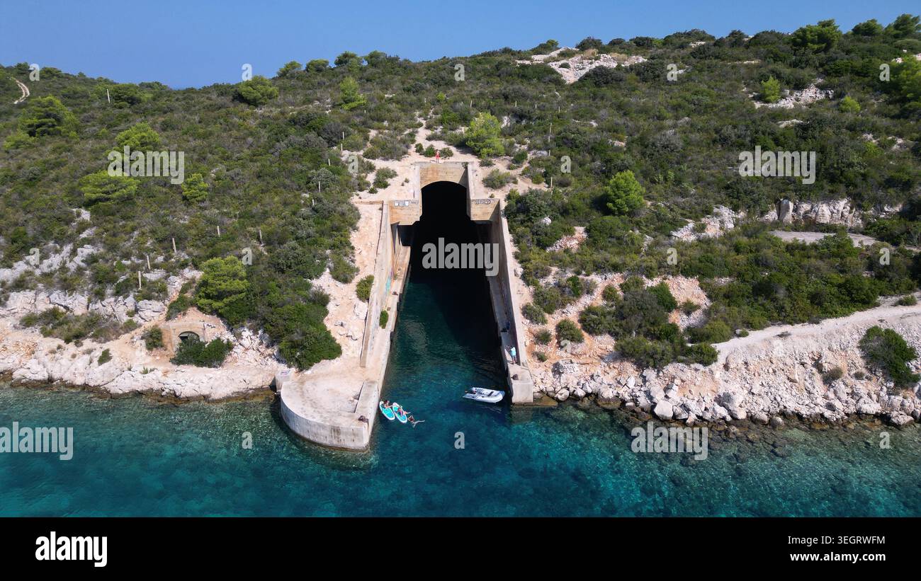 Aus der Vogelperspektive des unterirdischen Bootsschutzes der jugoslawischen Armee Potkop Parja mit Menschen auf Paddleboards im türkisfarbenen Wasser in Rogacic, Splitsko-dalmatinska Stockfoto