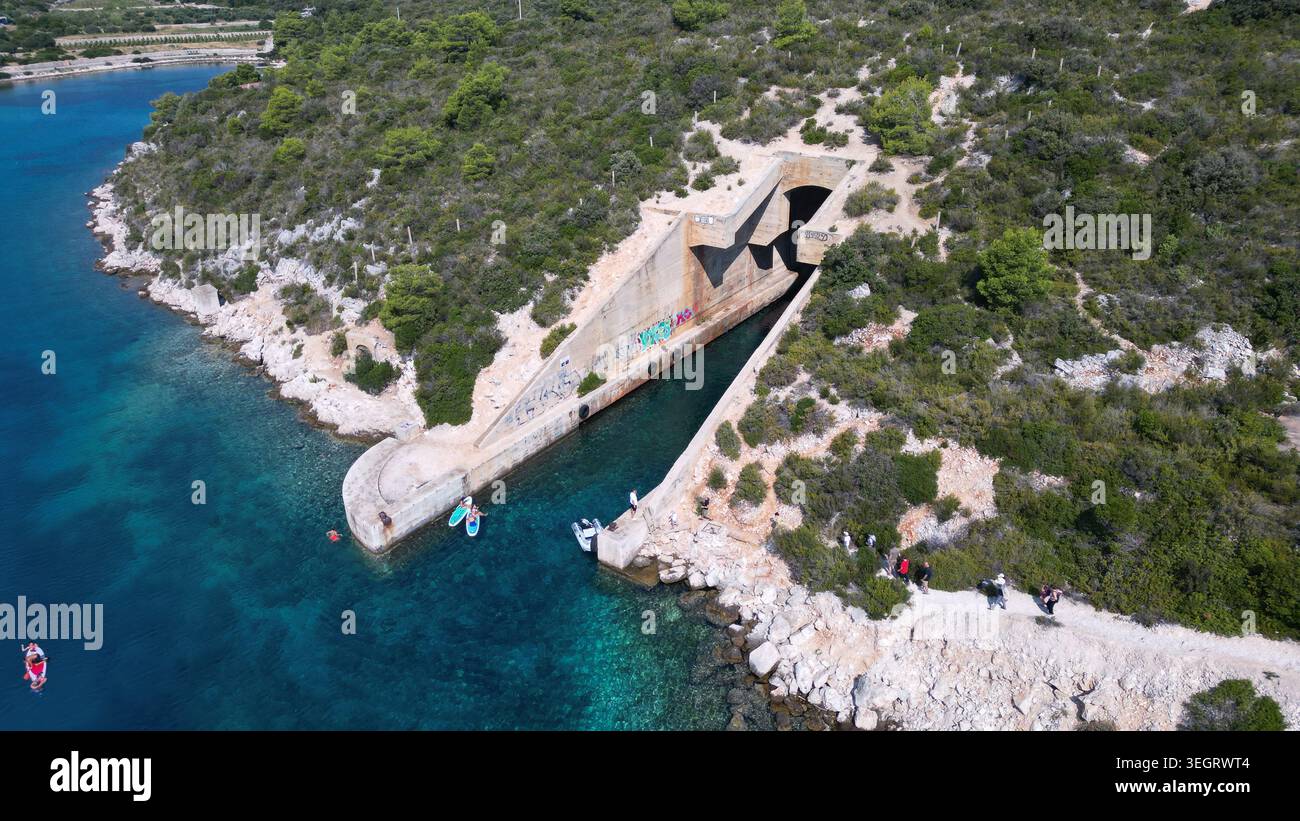 Aus der Vogelperspektive auf die jugoslawische Armee unterirdische Bootsunterkunft Potkop Parja, die in die felsige Küste mit türkisfarbenem Wasser und üppigem Grün in Rogac gehauen wurde Stockfoto