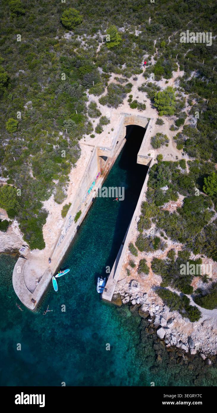 Aus der Vogelperspektive auf die jugoslawische Armee unterirdische Bootsunterkunft Potkop Parja mit türkisfarbenem Wasser und üppiger grüner Vegetation in Rogacic, Splitsko-dalmatinska Stockfoto