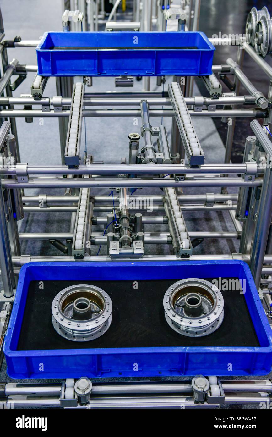 Metallteile für die Automobilindustrie in einer blauen Kunststoffkiste auf einem automatisierten Fördersystem. Stockfoto