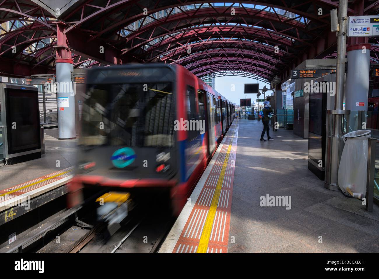 Der DLR-Zug fährt vom Bahnsteig am Bahnhof Canary Wharf in London ab und erfasst moderne städtische Verkehrsmittel und Pendlerfahrten. Stockfoto