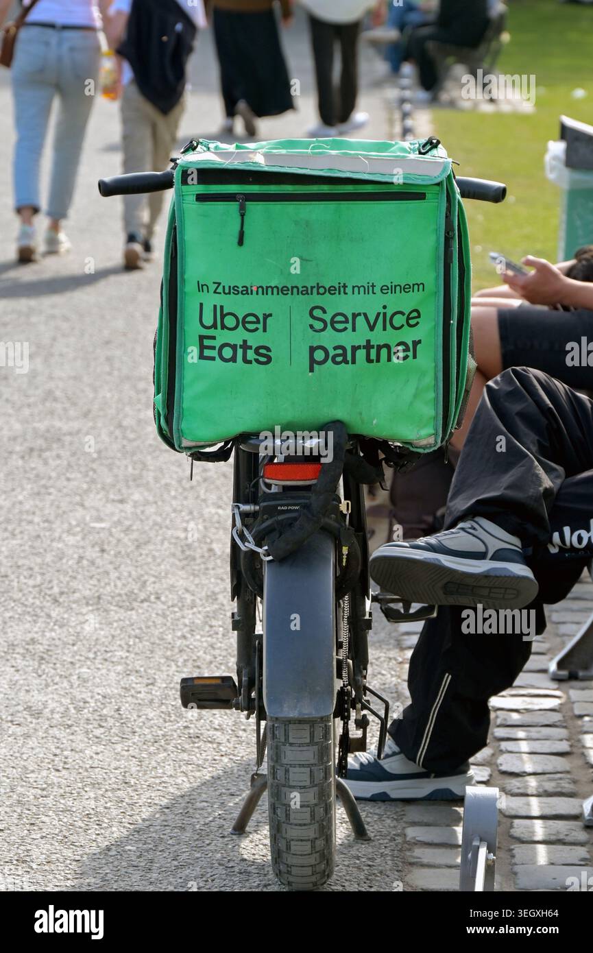Frankfurt, Deutschland - 11. April 2026 - Person, die für Uber arbeitet, sitzt auf einer Parkbank und wartet auf den nächsten Lieferauftrag. Stockfoto