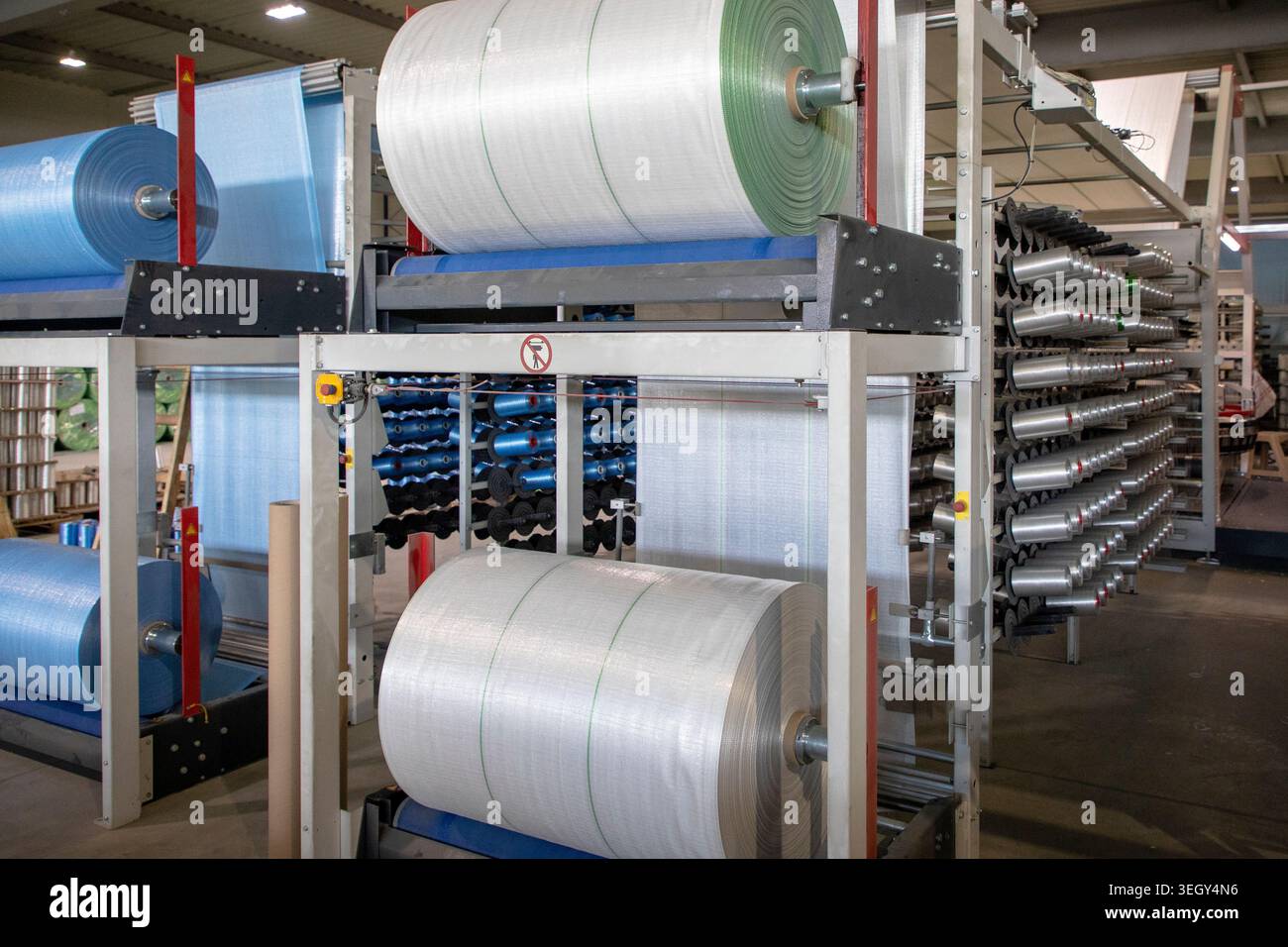 Industrielle Herstellung von Nylonfasern für die Sackherstellung mit automatisierten Maschinen und farbenfrohen Spulen in einem modernen Fabrikumfeld. Stockfoto
