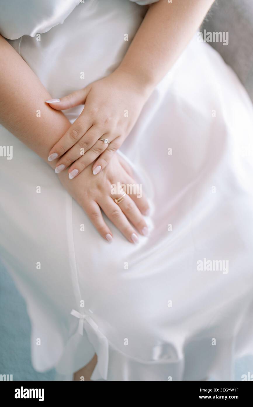 Elegante Hände mit Verlobungsring auf Satinkleid Stockfoto