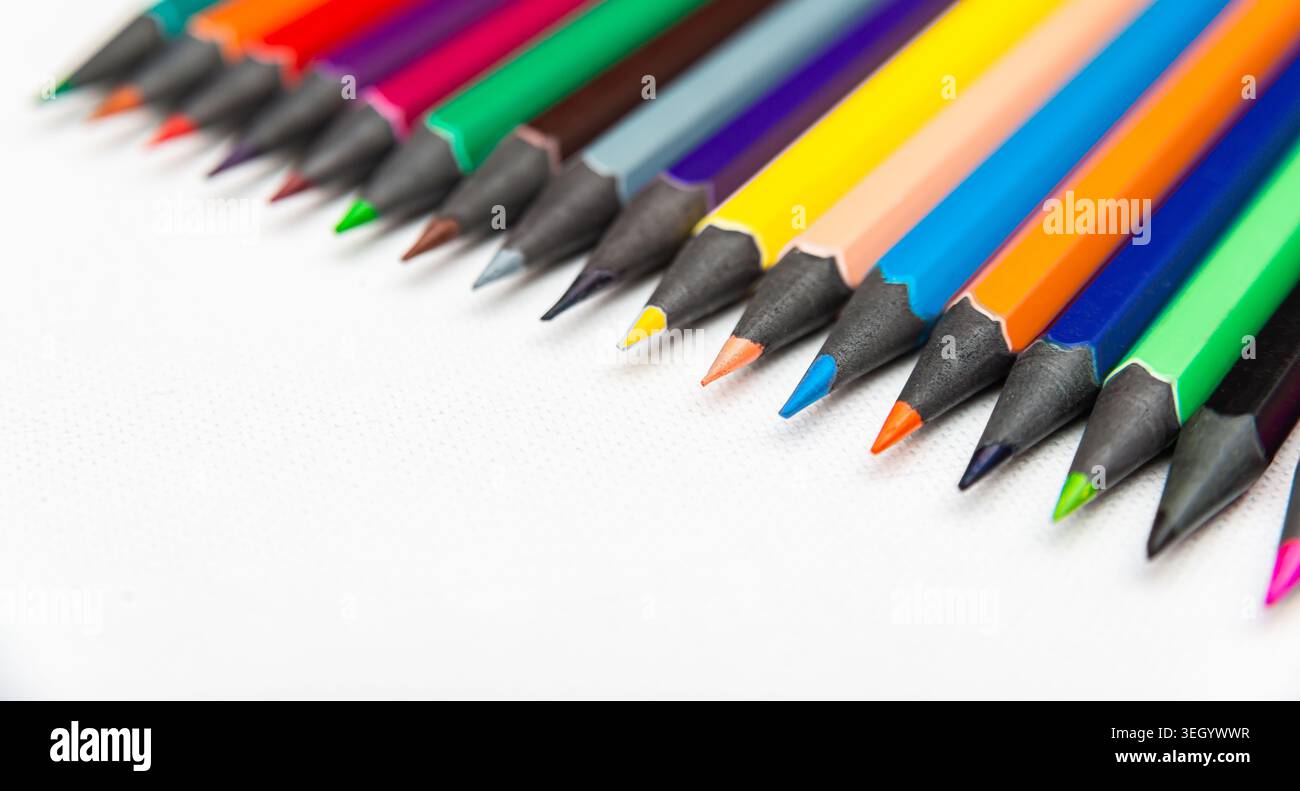 Bleistifte in verschiedenen Farben sind auf einer weißen Oberfläche angeordnet. Jeder Bleistift zeigt seine geschärfte Spitze. Sie sind bereit für kreative Aktivitäten. Stockfoto