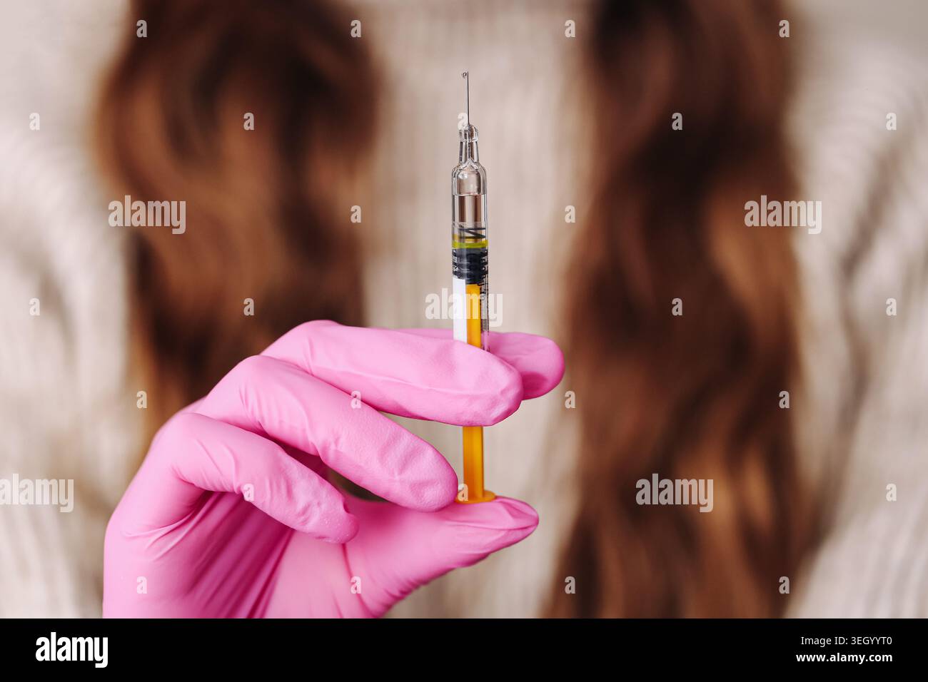 Medizinische Spritze in Schutzhandschuhnaht gehalten. Impfungs- und Behandlungskonzept mit Injektionstechnik im Innenbereich. Stockfoto