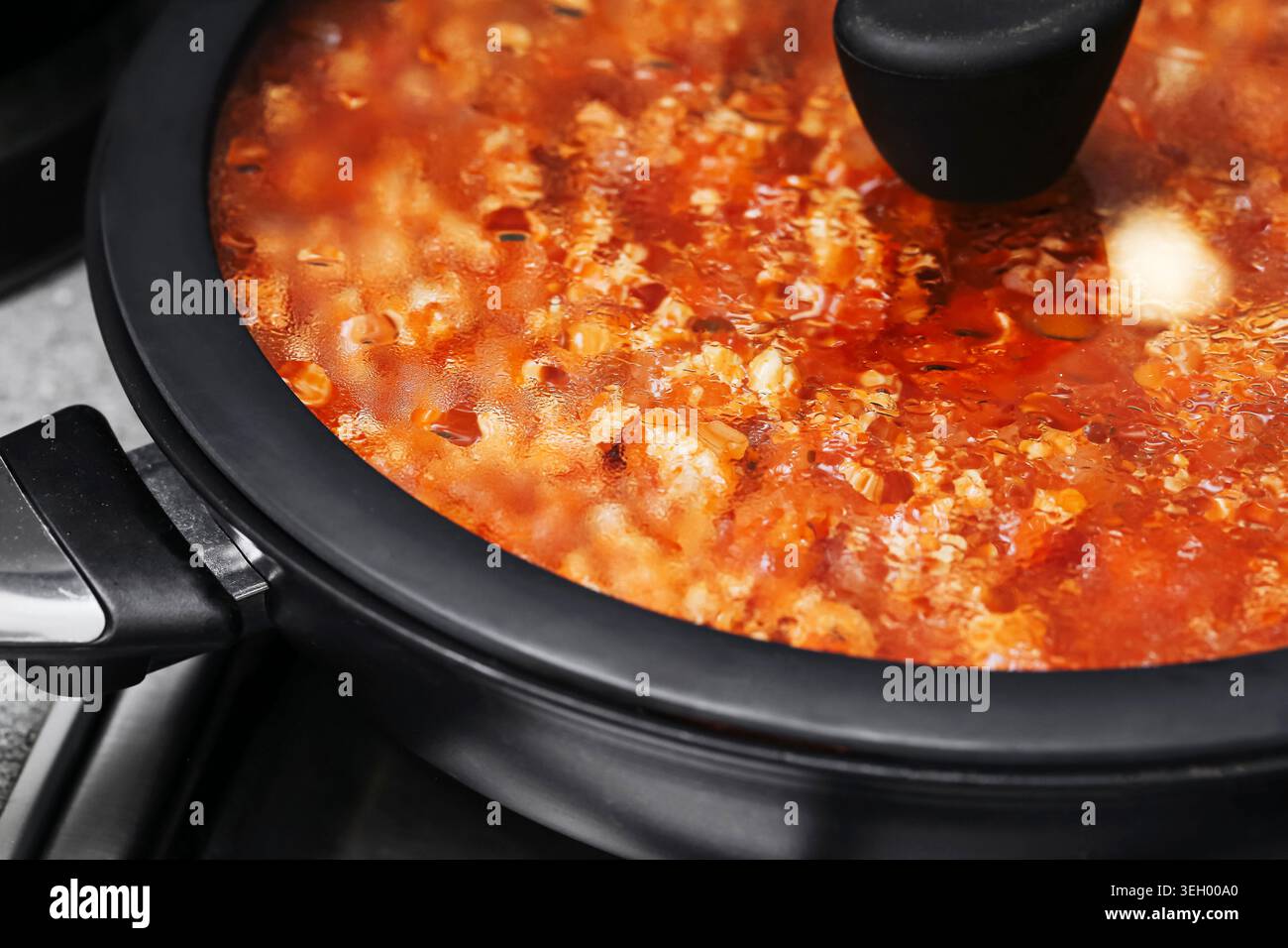 Hausgemachte Spaghetti-Sauce, die im Mehrkochfeld gekocht wird. Warme Pasta-Mahlzeit und traditionelle italienische Küche im Innenbereich. Stockfoto