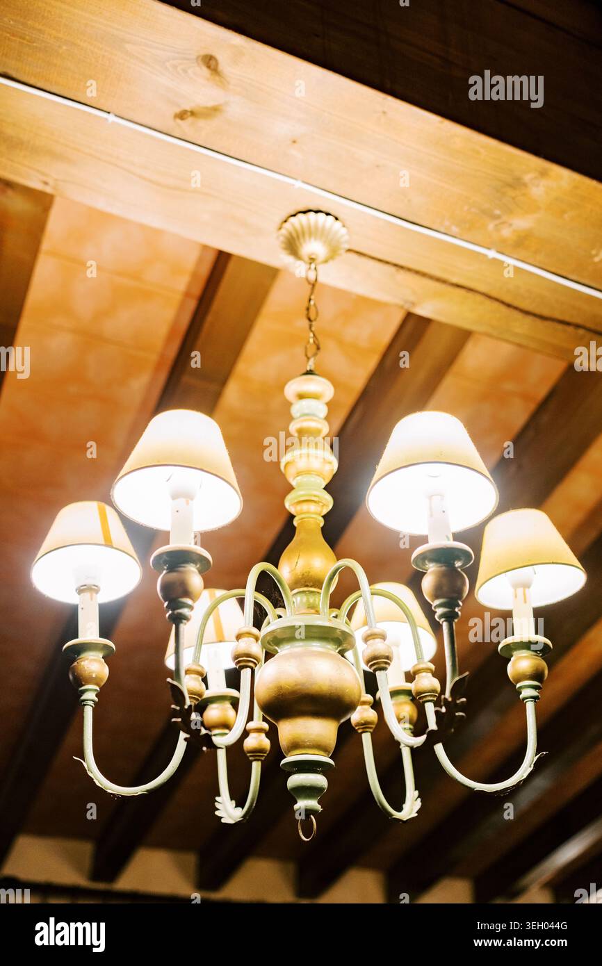 Vintage-Kronleuchter aus Messing mit Lampenschirmen im rustikalen Interieur Stockfoto