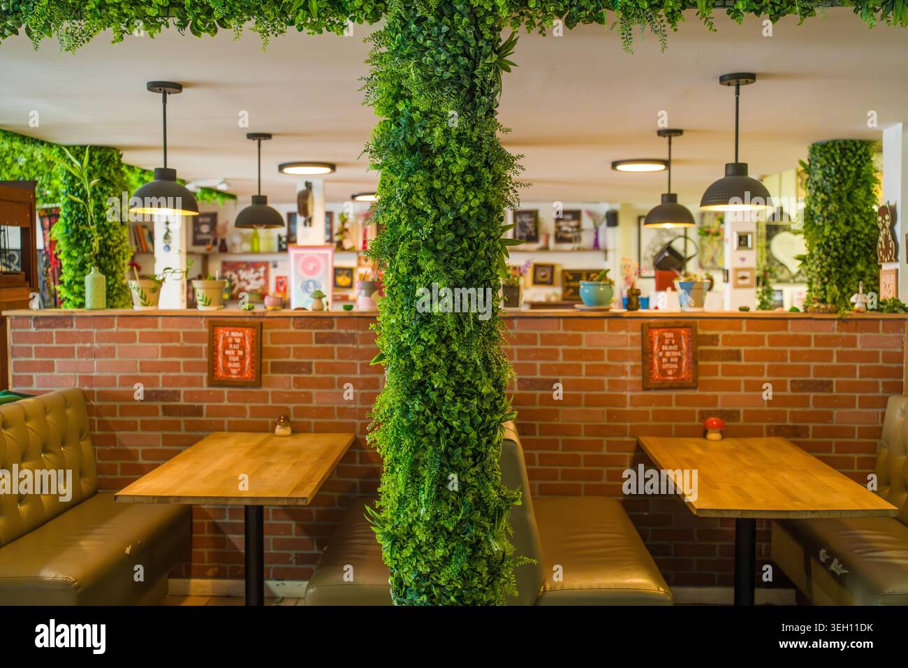 USA, Hollywood, FL - 03. Mai 2026: Inmitten von Mystic Coffee steht eine zentrale architektonische Säule mit künstlichen Pflanzen. Stockfoto