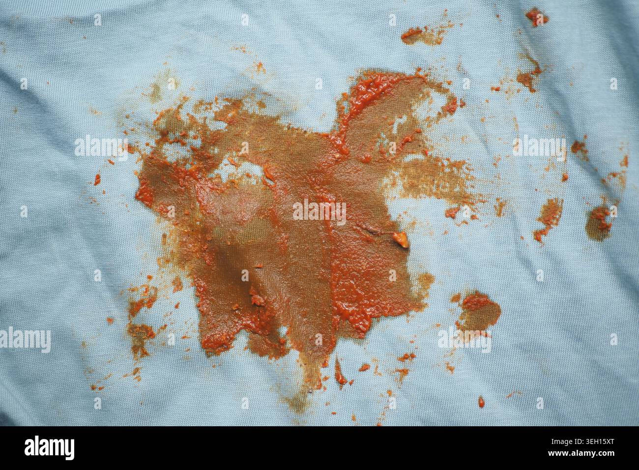 Soßenflecken auf hellblauem Stoff beim Kochen Stockfoto