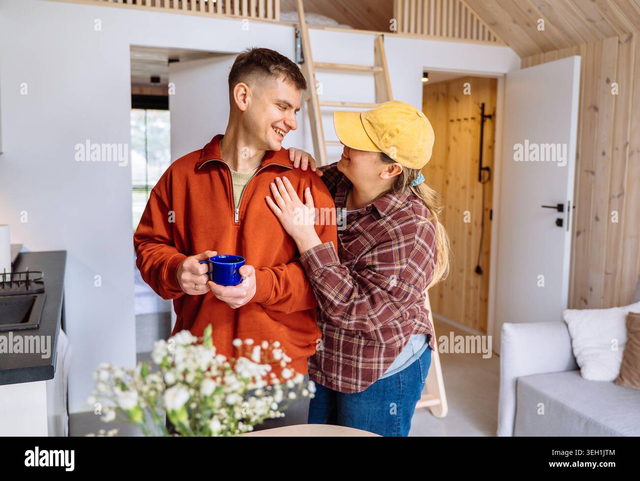 Glückliches Paar teilt einen gemütlichen Morgen in einer modernen Waldhütte mit skandinavischem Interieur Stockfoto