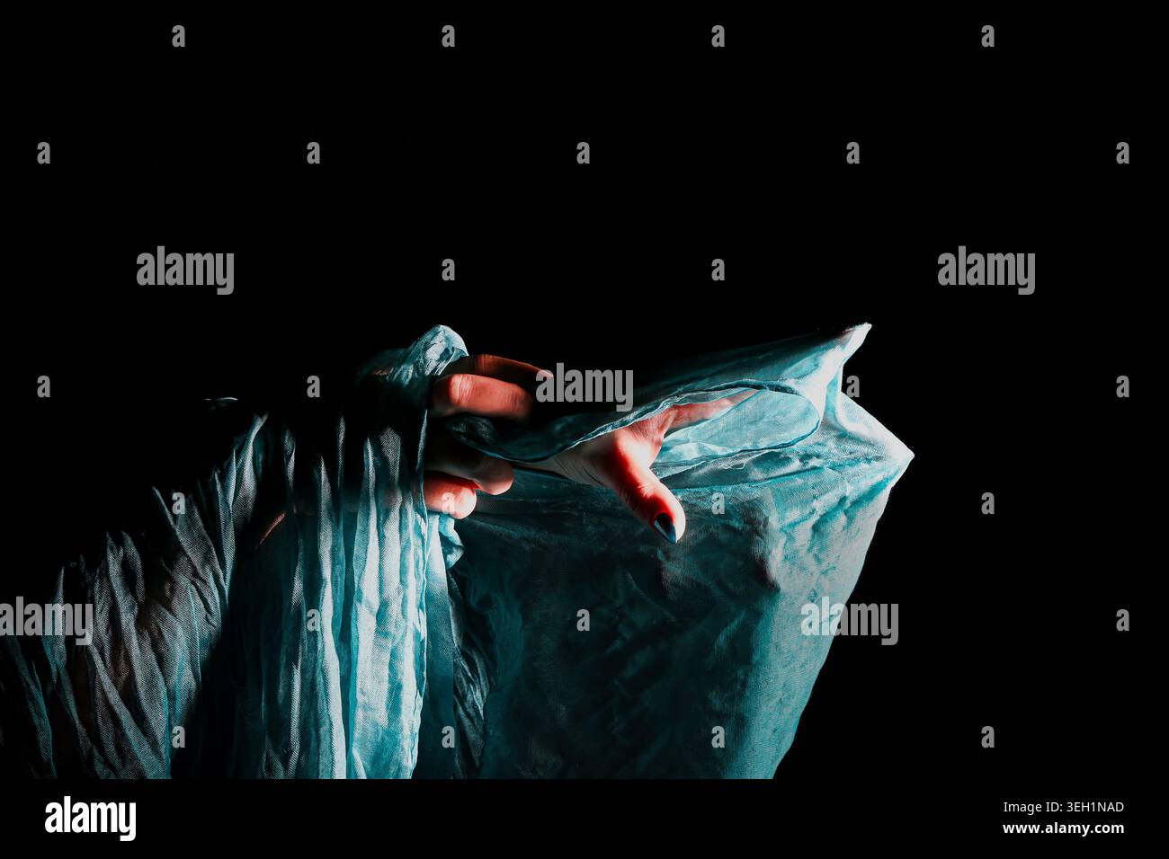 Verborgene menschliche Figur unter durchscheinendem blauem Stoff. Symbolische Darstellung von geistiger Gesundheit, Angst, Isolation, emotionaler Belastung und psychologischer Stockfoto