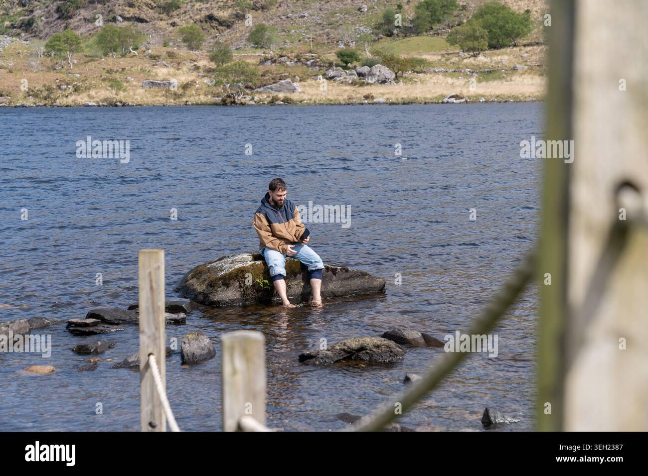 Mann, der sich wieder mit der Natur verbindet, während er ein Mobiltelefon benutzt Stockfoto