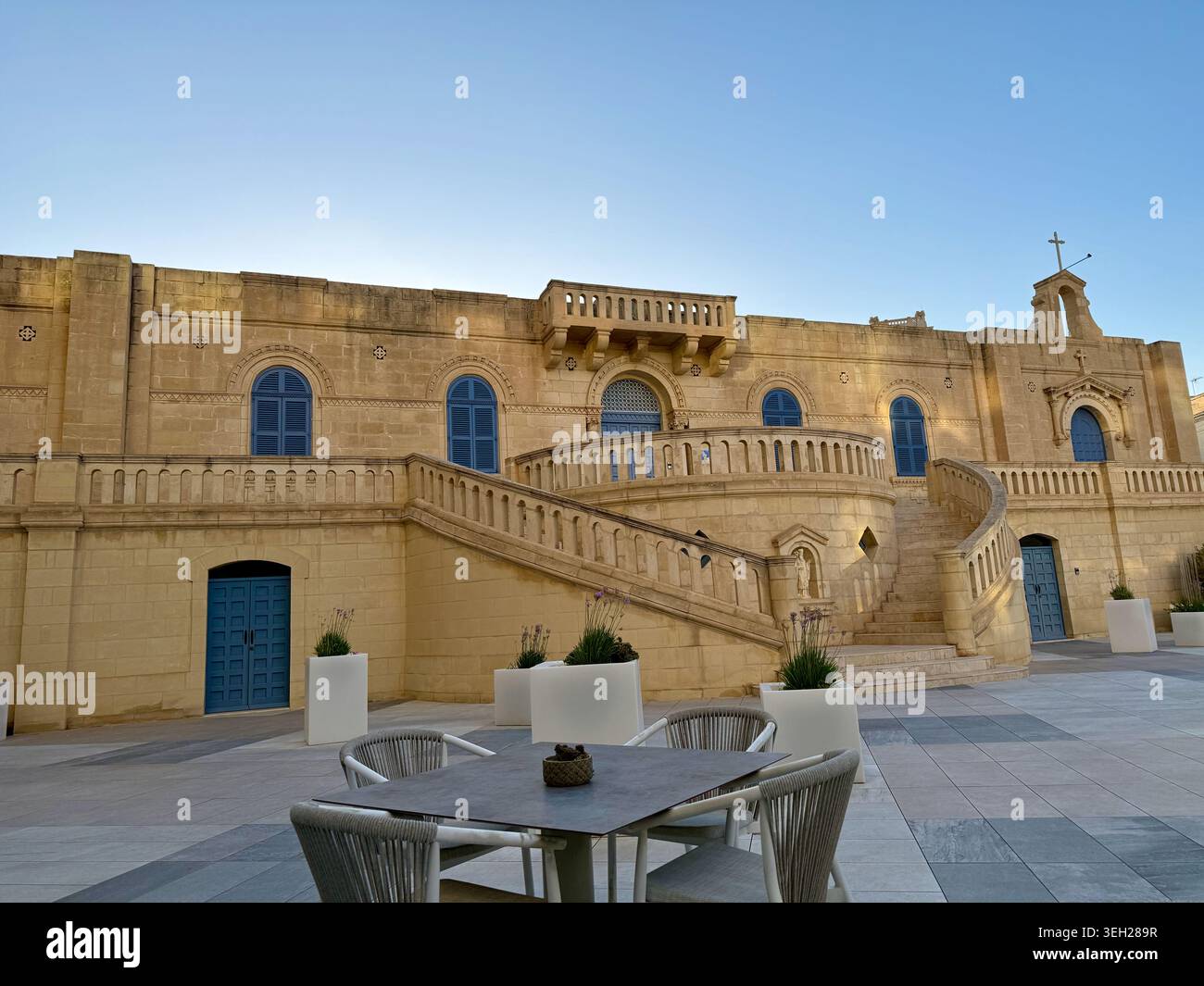 Malta Gozo goldene Kalksteinkirche mit blauen Türen und Außenterrasse - Smartphone-aufgenommenes Stockfoto