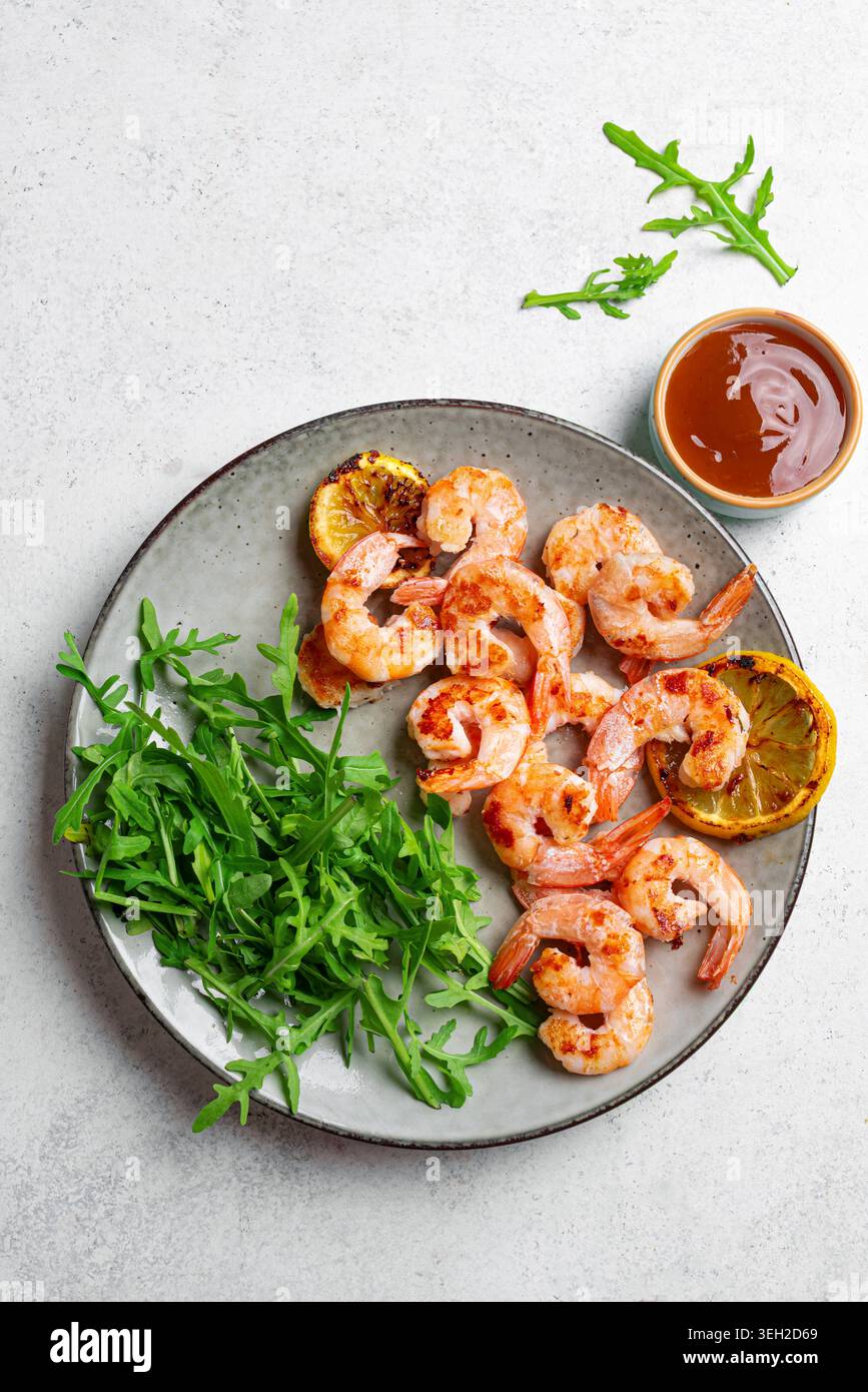 Gegrillte Garnelen, Garnelen mit Zitrone, Rucola-Salat und süße Chili-Sauce, Blick von oben. Scharfe gebratene Garnelen. Low Carb Snack. Stockfoto