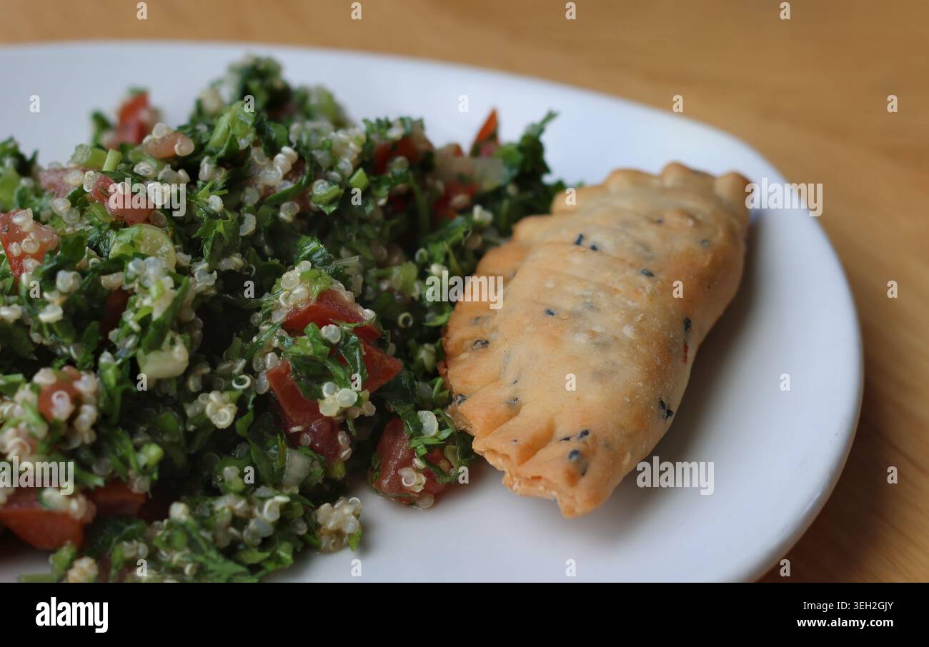 Ein Palte von Tabbouleh mit Quinoa und einem frittierten Käse Sambousek. Stockfoto