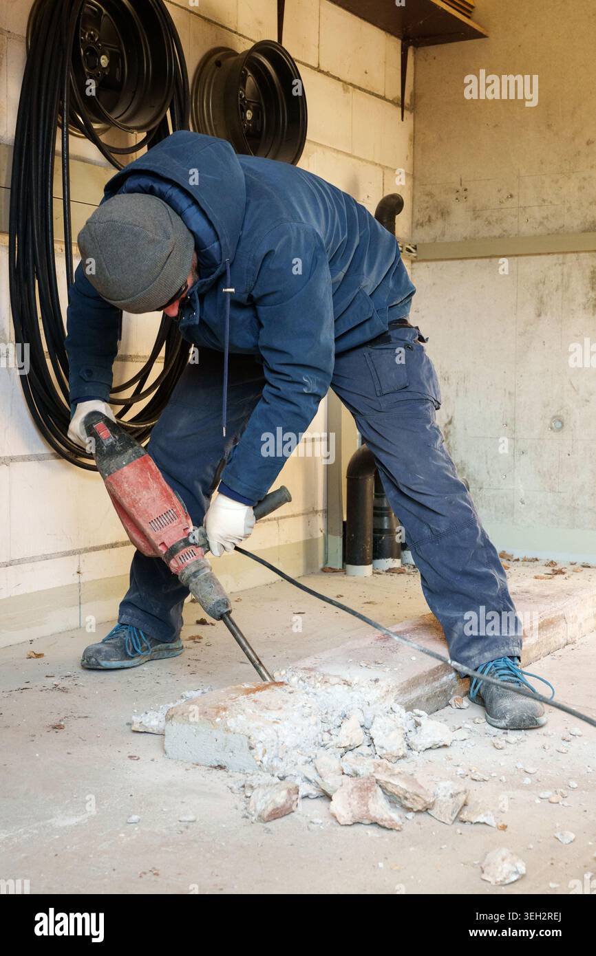 Arbeiter, der während der Renovierung des Hauses Betonboden abriss Stockfoto