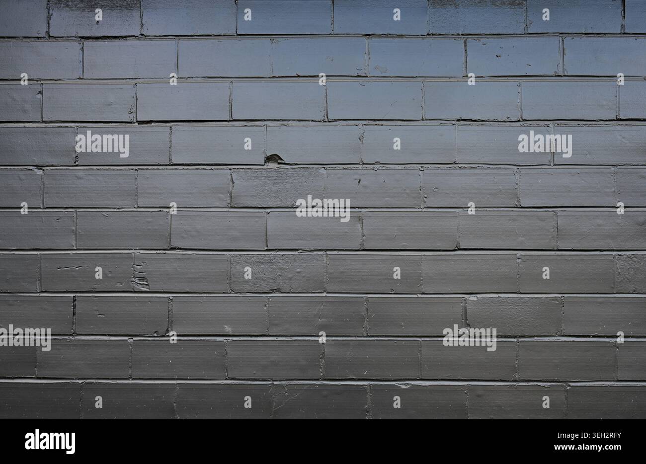 Schwarz lackierte Schlackenblockwand mit glatten, unebenen Mörtelfugen, abgesplitteten Blöcken, meist glatte Oberflächen mit einigen rauen Stellen Stockfoto