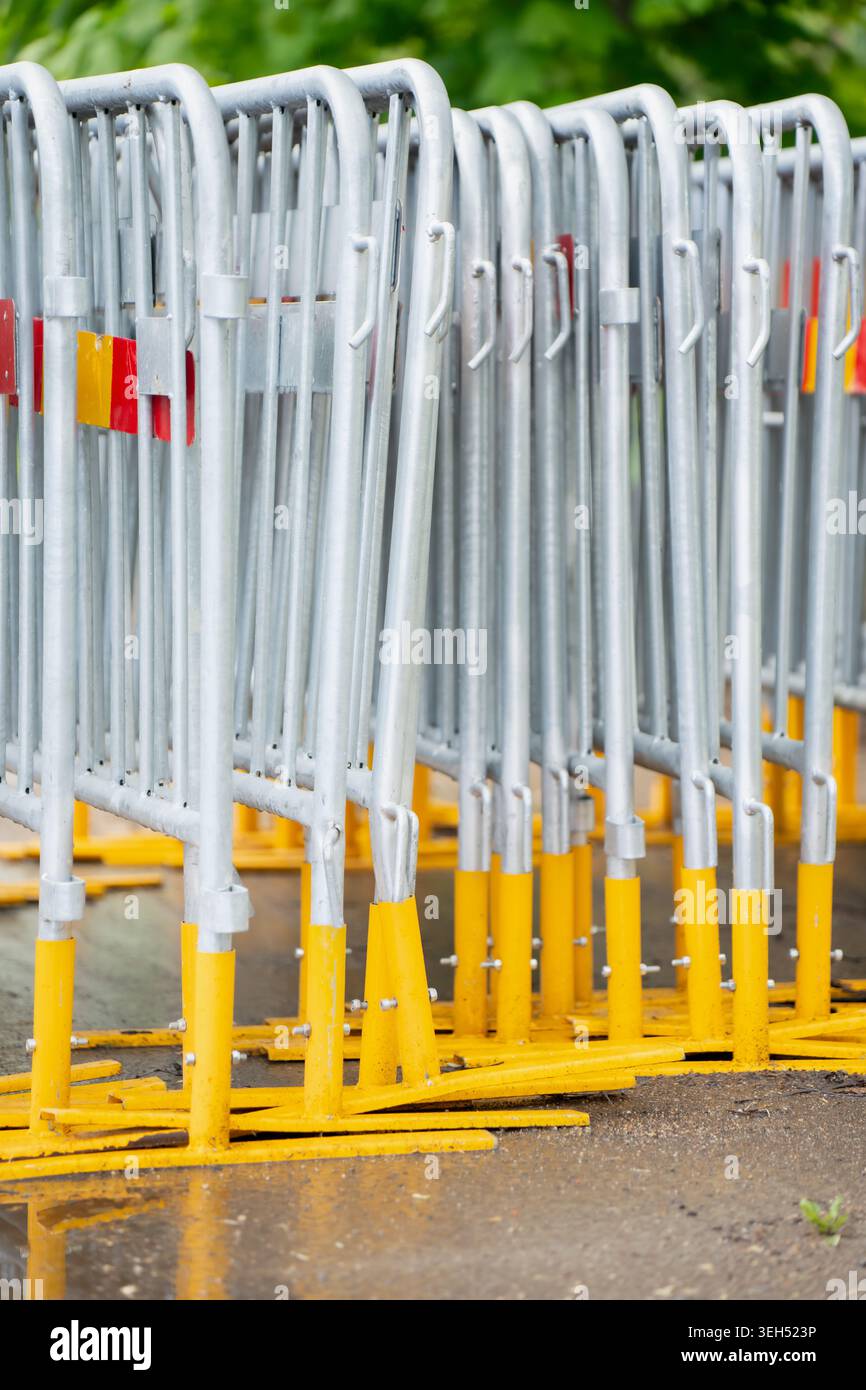 Temporäre Stahlzaun-Barrikadenkonstruktionen mit hellgelben Füßen im Freien für die Sicherheit auf der Baustelle oder für die Ausrichtung der Festivalbesucher Stockfoto