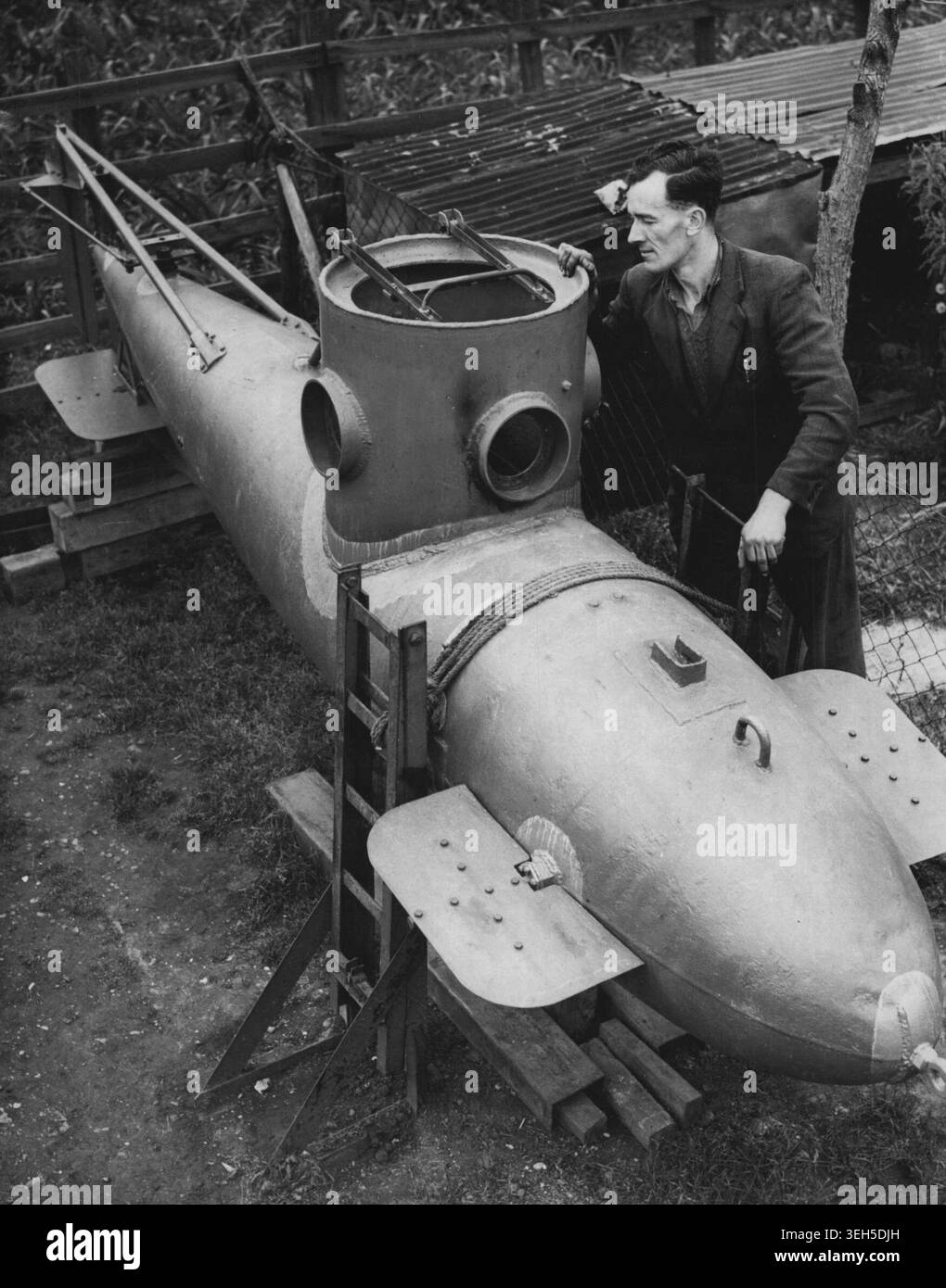 Ein-Mann-U-Boot im „Fertighaus“-Garten gebaut – Mr. Frank Russell blickt in den Turm seines ein-Mann-U-Bootes im Garten seines „Fertighauses“ in Biggleswade, Bedfordshire, und das einzige im Hinterhof gebaute ein-Mann-U-Boot steht nun vor der Fertigstellung. Das Boot wurde in den letzten zwei Jahren von Mr. Frank Russell zu einem Preis von £ 120 gebaut. Sie besteht aus einer Stahlplatte mit einem Durchmesser von ca. 30 cm und wiegt bei voller Beladung etwa eine halbe Tonne Russell plant, das U-Boot Anfang nächsten Monats per LKW nach Bedford zu transportieren und es in eine Tiefe von 15 Metern zu bringen. In der Ouse. Stockfoto