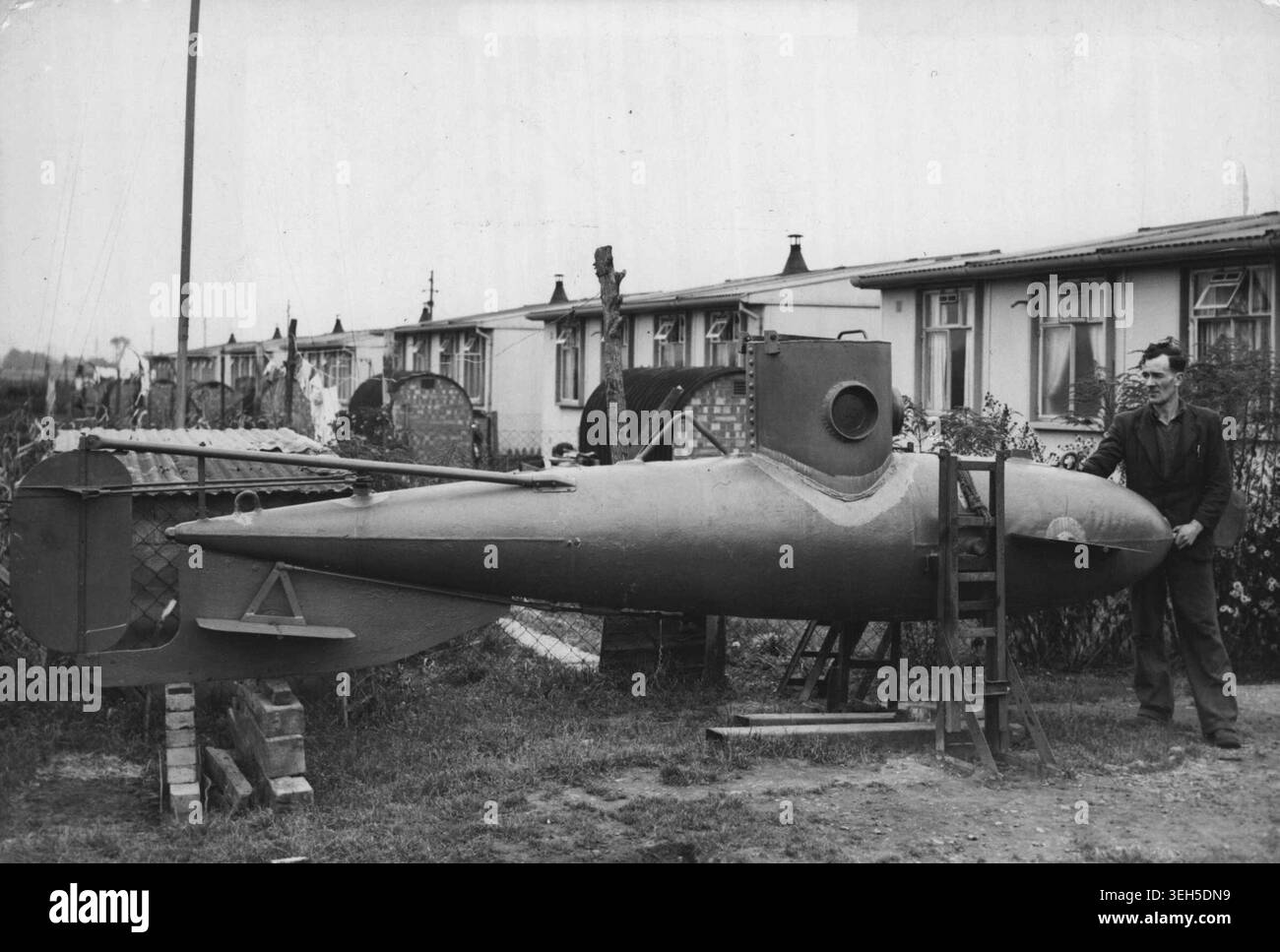 Ein-Mann-U-Boot im „Prefab“-Garten gebaut – Mr. Frank Russell mit seinem ein-Mann-U-Boot im Garten seines „Fertighauses“ in Biggleswade, Bedfordshire, steht das einzige im Hinterhof gebaute ein-Mann-U-Boot vor der Fertigstellung. Das Boot wurde in den letzten zwei Jahren von Mr. Frank Russell für £ 120 gebaut. Sie besteht aus einer Stahlplatte mit einem Durchmesser von ca. 30 cm und wiegt bei voller Beladung etwa eine halbe Tonne Russell plant, das U-Boot Anfang nächsten Monats per LKW nach Bedford zu transportieren und es in eine Tiefe von 15 Metern zu bringen. In der Ouse. Oktober 1950. Stockfoto