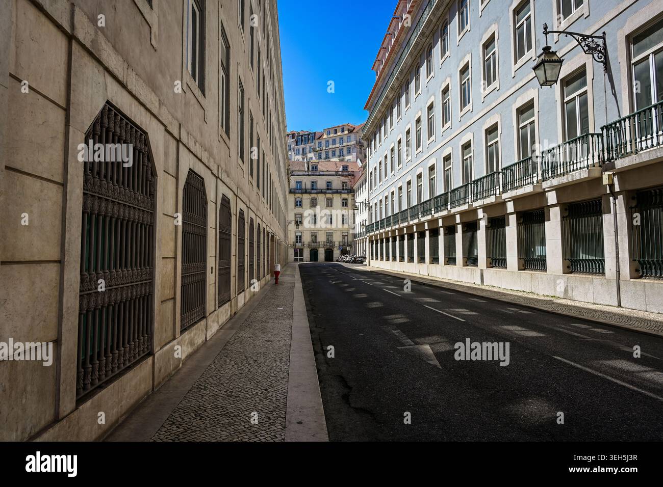 Eine ruhige Straße in Lissabon, gesäumt von eleganten historischen Gebäuden, schmiedeeisernen Balkonen und klassischer portugiesischer Architektur. Stockfoto