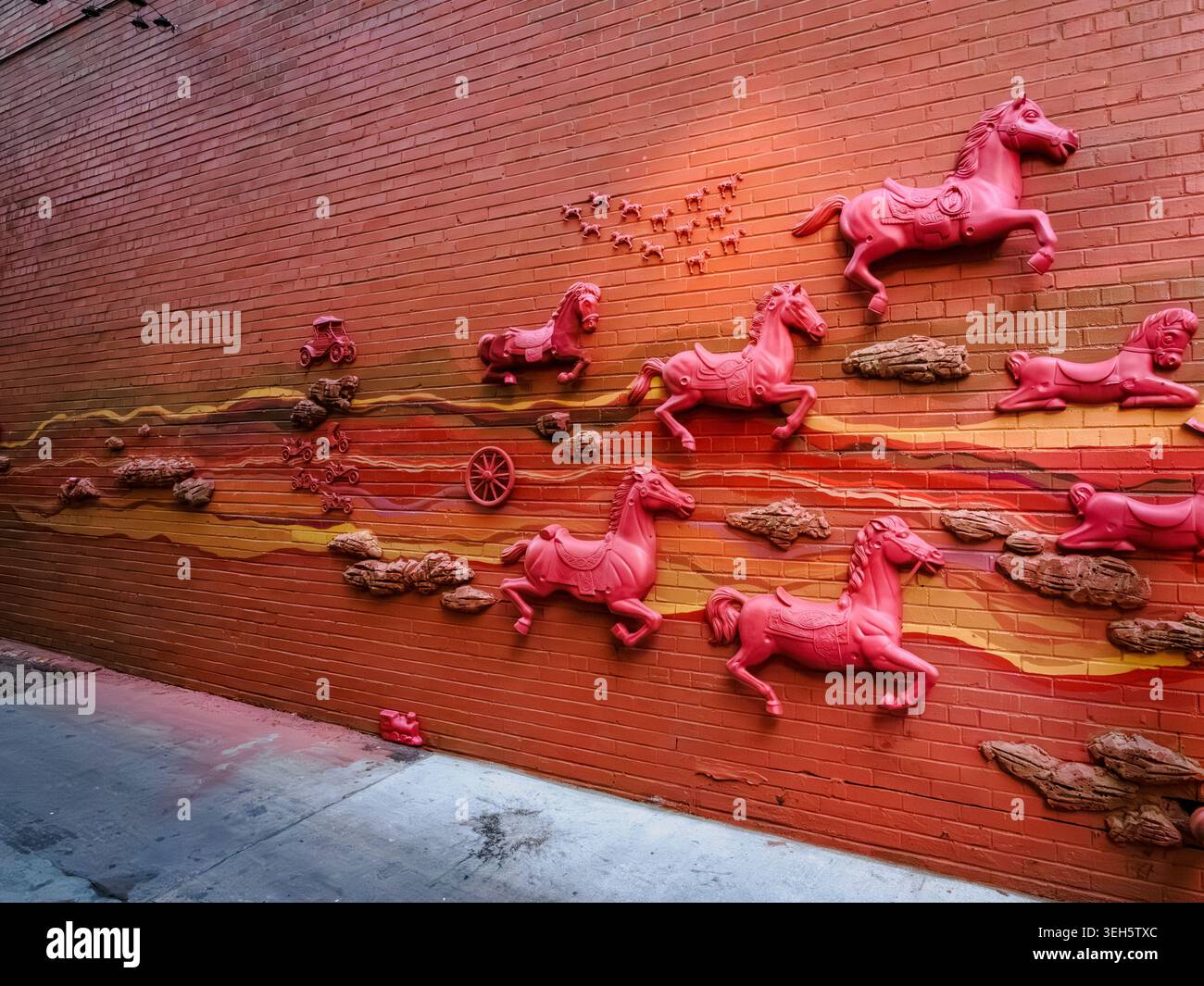 Rotes Reliefgemälde mit Pferden an einer orangen Backsteinmauer an der 16th Street in Denver, Colorado Stockfoto