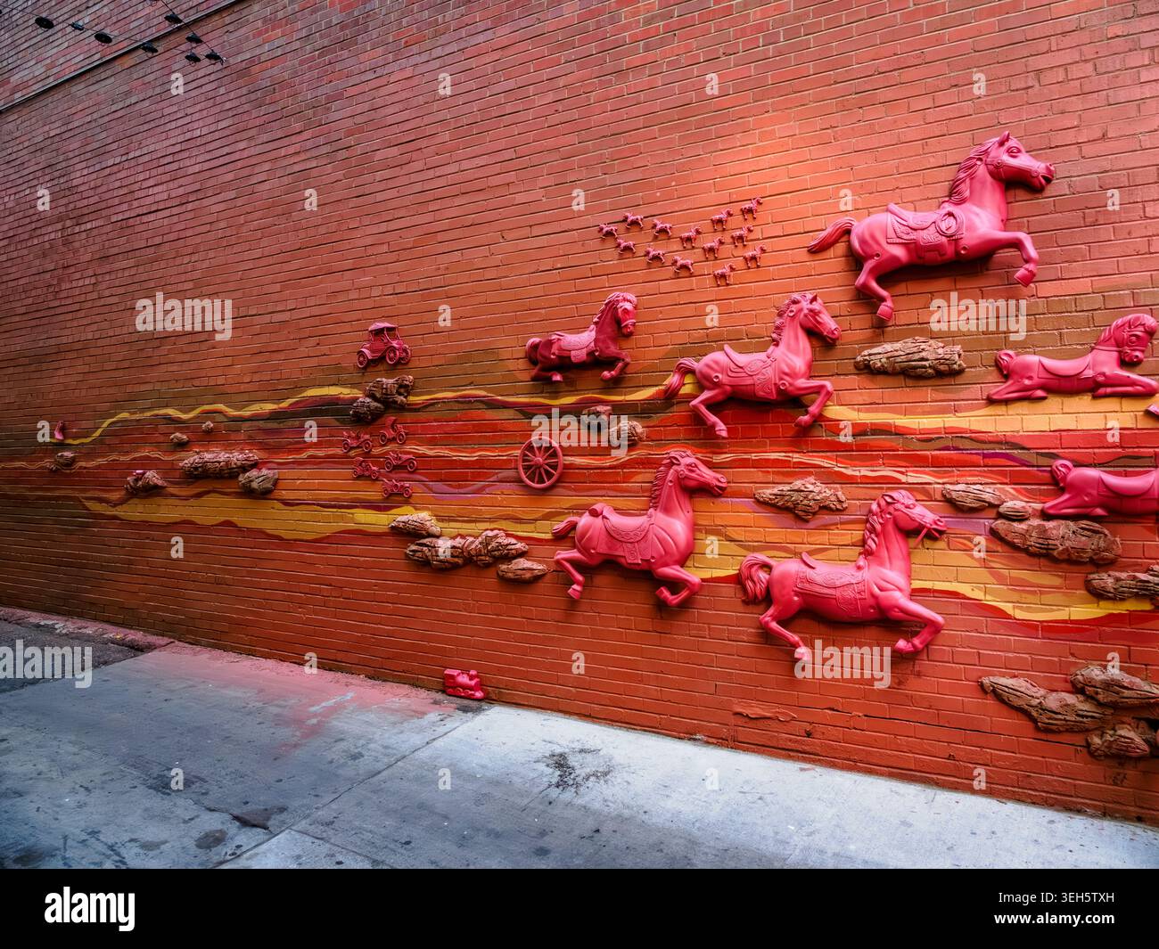 Rotes Reliefgemälde mit Pferden an einer orangen Backsteinmauer an der 16th Street in Denver, Colorado Stockfoto