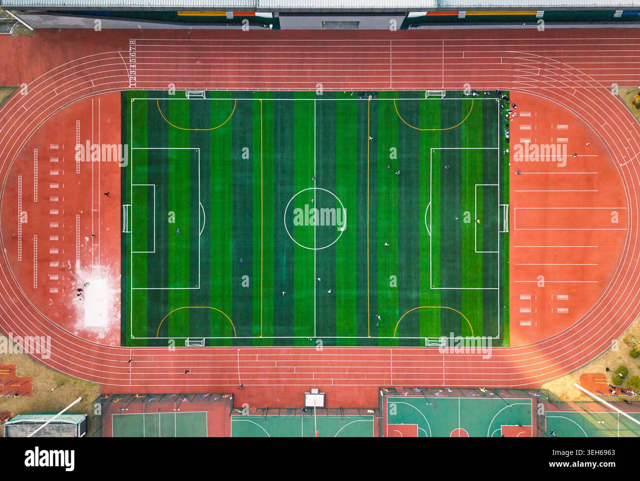 Lebhaftes grünes Fußballfeld, umgeben von einer roten Laufbahn in einem Outdoor-Sportkomplex Stockfoto