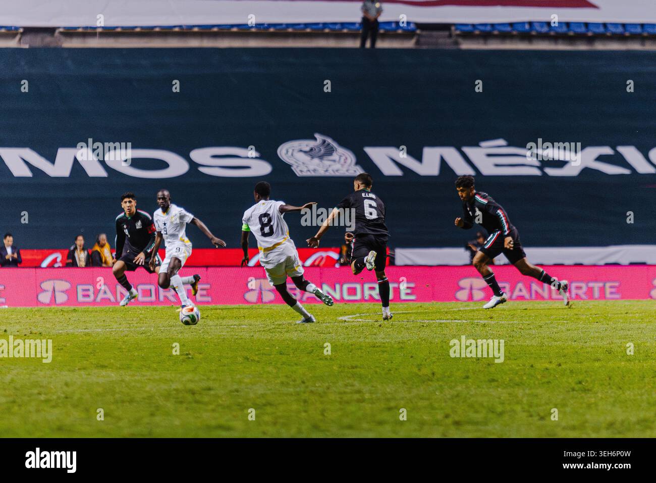 Ghana-Fußballspieler treiben den Ball während eines Offensive-Spiels gegen die defensiven Verfolgungen der mexikanischen Mannschaft nach vorne. Stockfoto