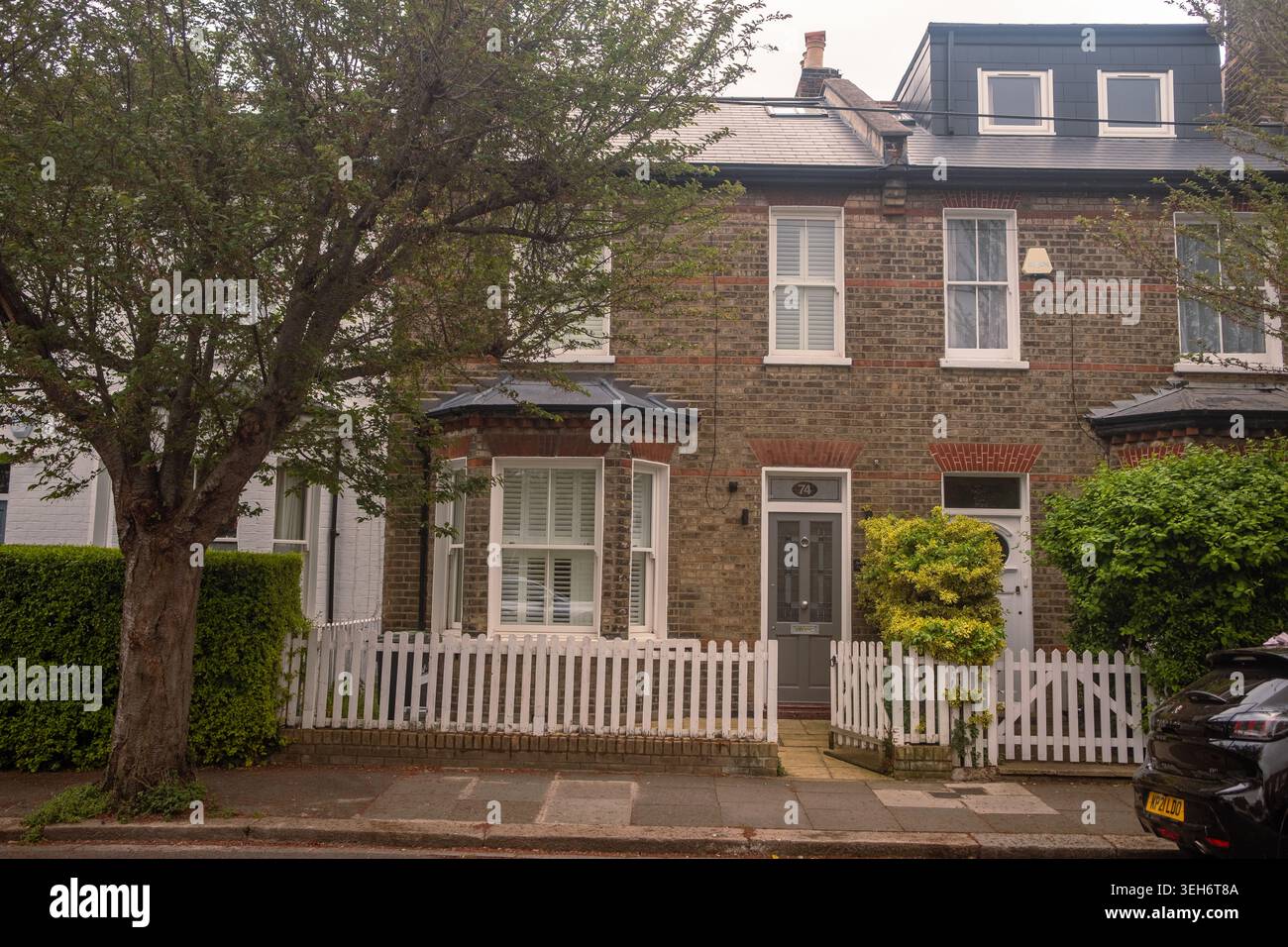 LONDON – 15. APRIL 2026: BRACKENBURY VILLAGE W6 – Haus aus der Zeit mit weißem Pflückzaun und blühendem Busch Stockfoto