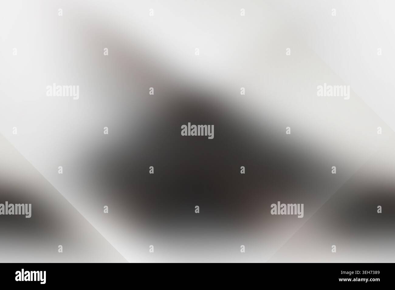 Eine abstrakte Komposition mit weichem, unscharfem Hintergrund und einer markanten dunklen, diamantförmigen geometrischen Form in der Mitte. Stockfoto