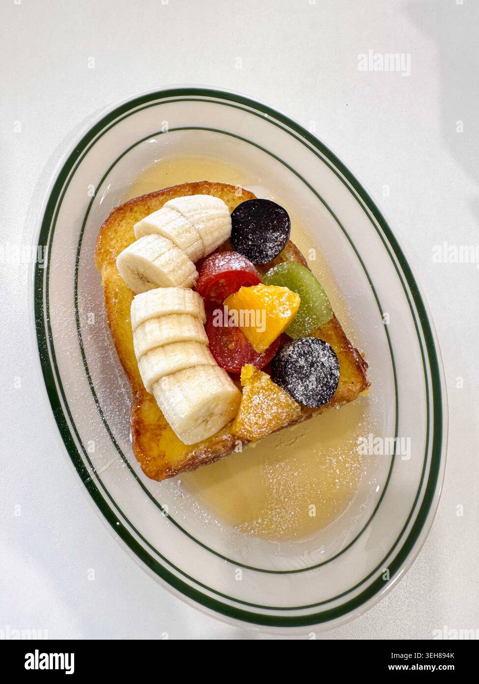 Nahaufnahme von süßem französischem Toast mit frischen Früchten wie Banane, Kiwi, Trauben und Orangenscheiben. Helles Frühstück und gesundes Brunch-Konzept. Stockfoto