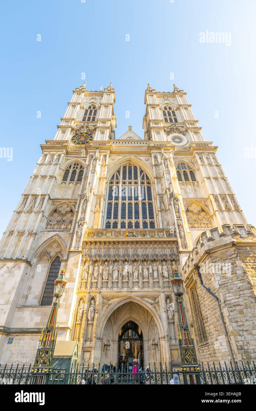 Westminster Abbey steht hoch in London. Touristen treffen sich am Eingang, um diese historische Stätte zu erkunden. Die Sonne scheint unter und hebt den Architekten hervor Stockfoto