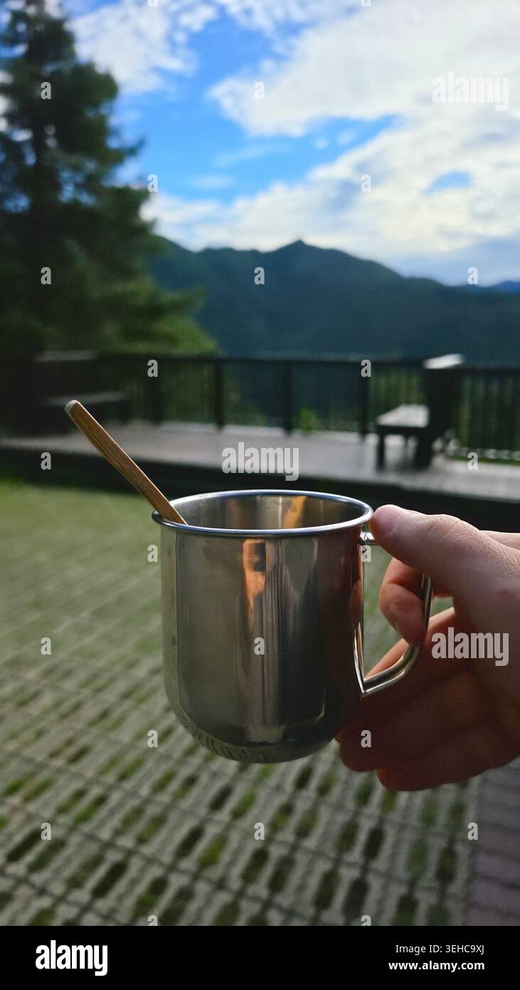 Morgenkaffee in einer Metalltasse auf einer malerischen Terrasse mit Bergblick in Taiwan Stockfoto