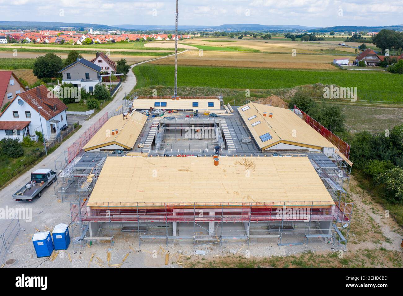 Igensdorf, Deutschland - 11. Mai 2024: Luftaufnahme einer großen Baustelle mit Arbeitern und Gerüsten, umgeben von Feldern und Häusern. Stockfoto