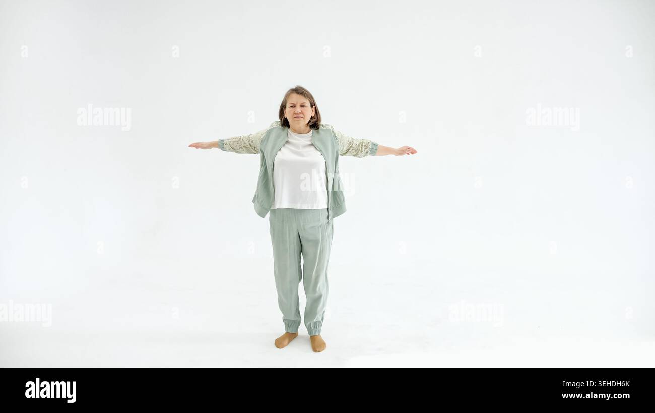 Entspannte Frau, Die Friedlich Ausbalanciert. Frau In Freizeitkleidung, Die An Übungen Zur Stabilität Und Selbstvertrauen Teilnimmt. Die Dame Der Mittelklasse Steht Mit Den Armen Stockfoto