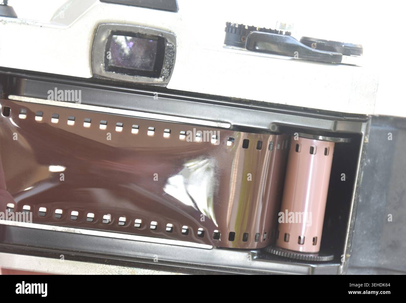 Manuelles Einlegen von Negativfilm auf eine einzelne Linse reflektiert in der hinteren Abdeckung Stockfoto