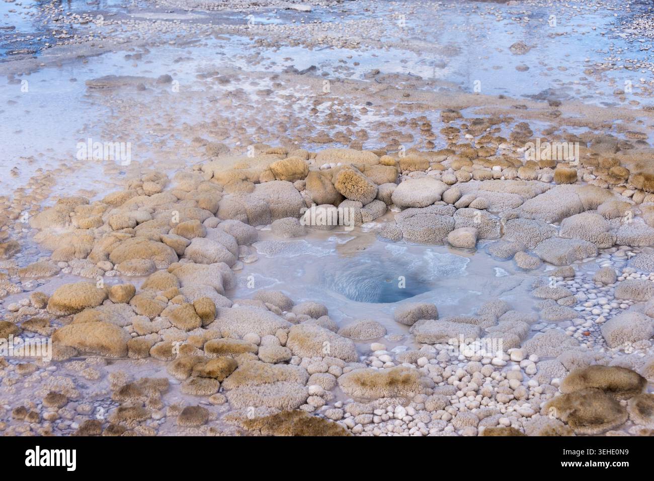 Blick aus der Nähe auf einen lebendigen geothermischen Thermalpool, umgeben von Mineralablagerungen und Dampf Stockfoto