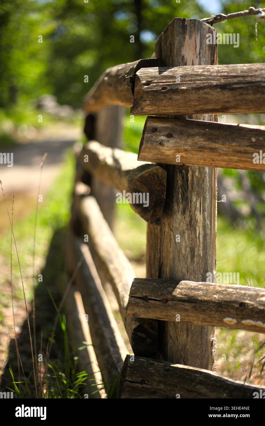 Aus nächster Nähe betrachten Sie einen rustikalen Holzzaun, der entlang eines staubigen Landwegs oder Wanderweges verläuft. Stockfoto