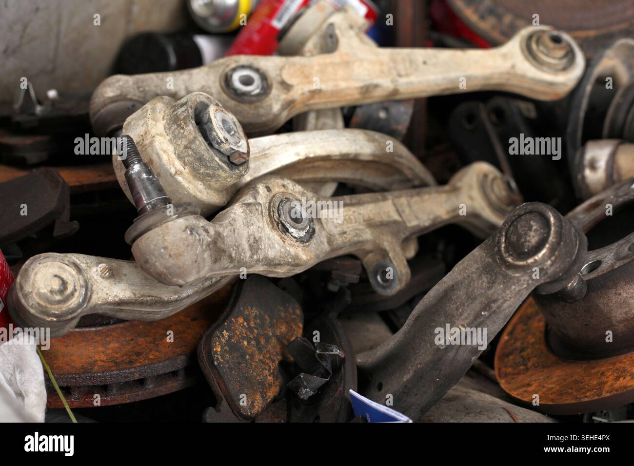Entsorgte Querlenker der Fahrzeugaufhängung und rostige Bremsbeläge in einem Schrotthaufen aus Schwermetall. Stockfoto