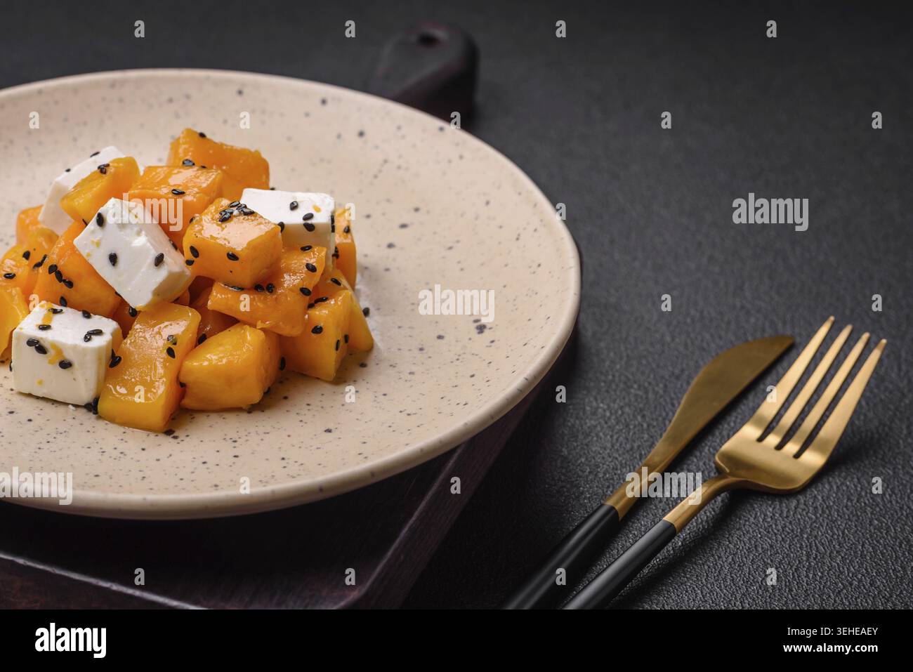 Essen, köstlicher saftiger Salat aus gegrilltem Kürbis mit Fetakäse, Gewürzen und Sesamsamen auf einer Keramikplatte Stockfoto