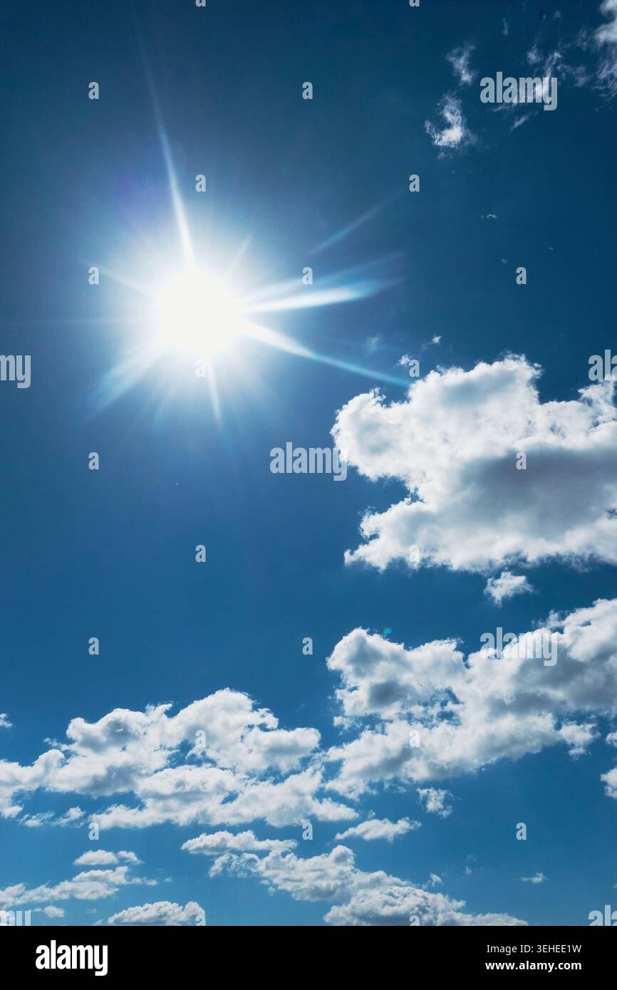 Heller Sonnenaufgang an einem tiefblauen Himmel mit verstreuten weißen Wolken, sonnigem Wetter und stimmungsvollem Kopierraum Stockfoto